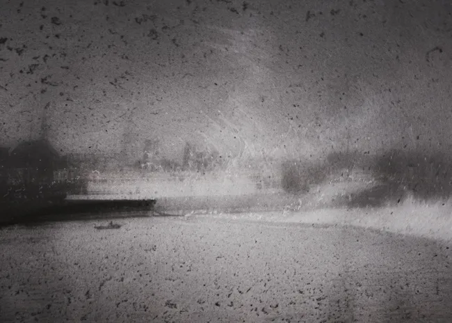 A black and white photograph depicting a river with a boat, surrounded by trees and buildings under a cloudy sky. The image appears textured, resembling an old or damaged photo.