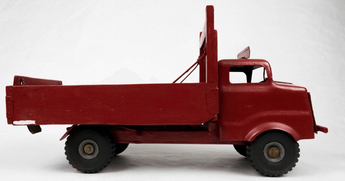 A vintage red toy truck viewed from the side.