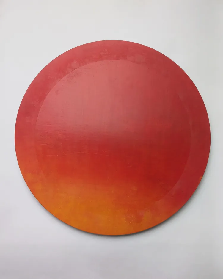 A circular artwork featuring a gradient transitioning from deep red at the top to a bright orange at the bottom.