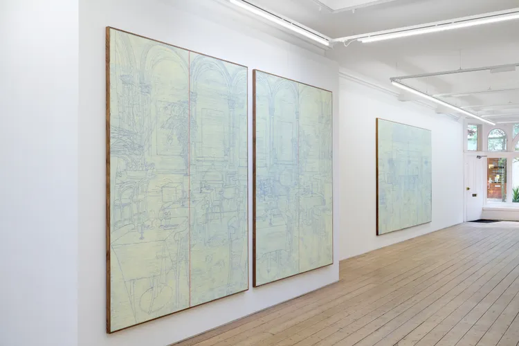 Two large, abstract paintings in light colors hanging on white walls in a spacious gallery with wooden flooring.