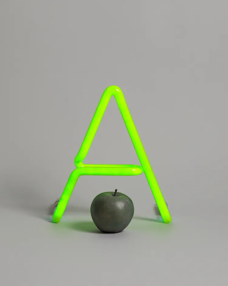 A green neon letter "A" next to a dark green apple.
