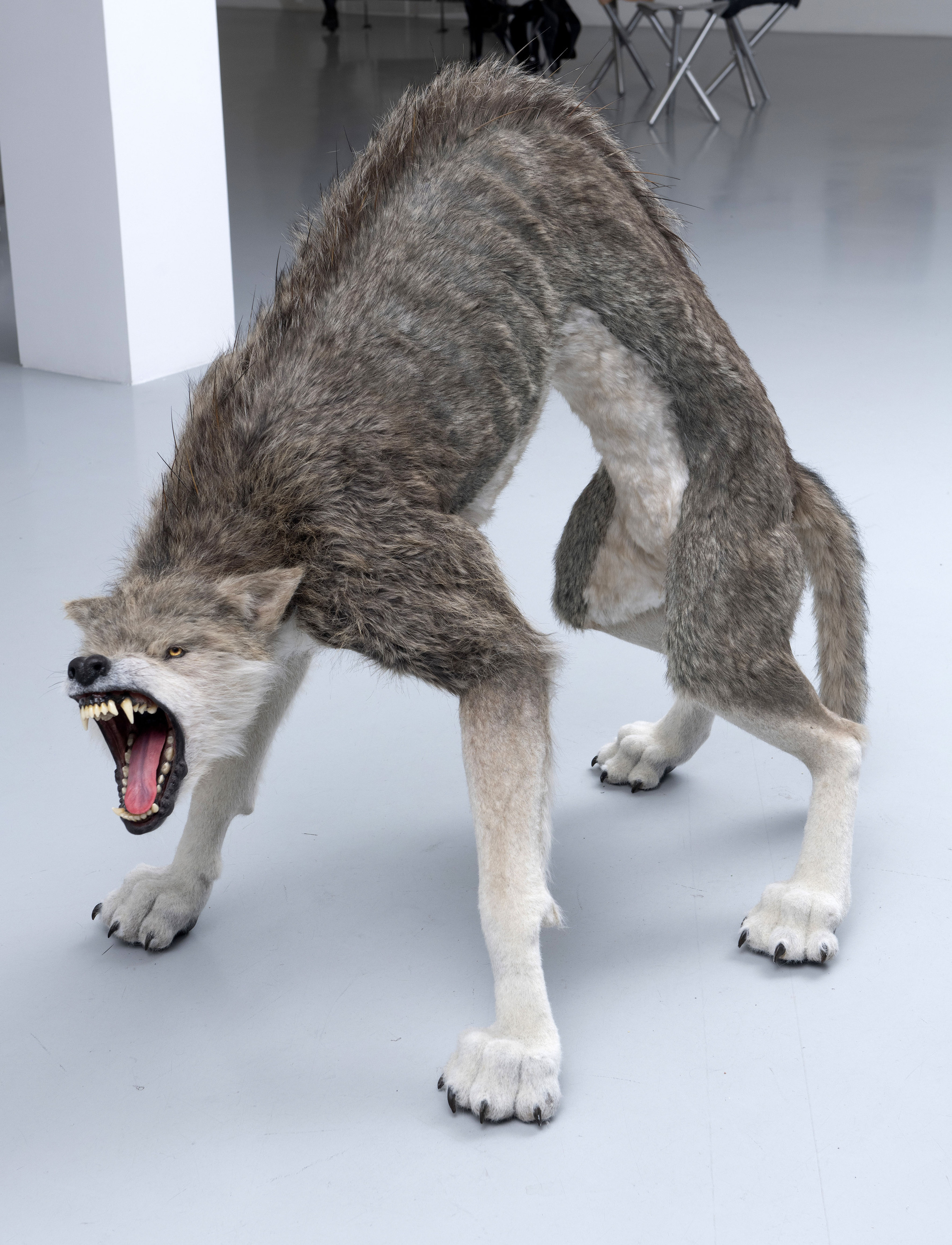 A large, aggressive-looking creature resembling a wolf, with elongated features and a threatening posture, standing on all fours in a modern indoor setting.