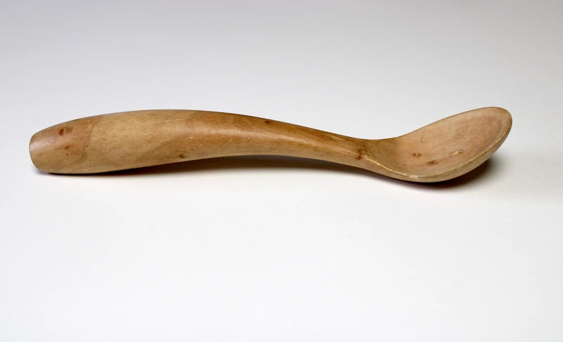 A wooden spoon with a curved handle and a shallow bowl.