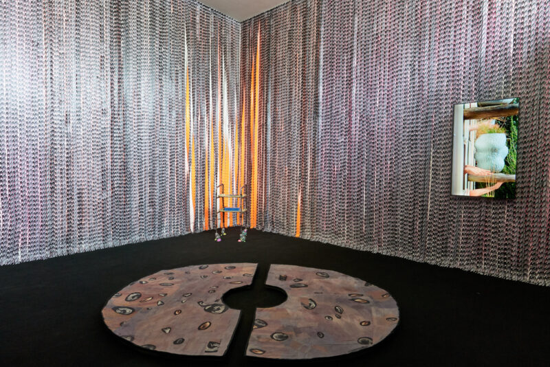 An art installation featuring a room with patterned walls, a round rug in the center, and a reflective screen on one side. | 2026 Southwark Park Galleries
