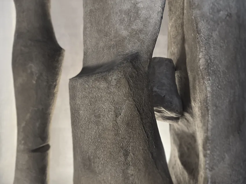 Abstract sculpture made of textured gray material with sharp and smooth edges.