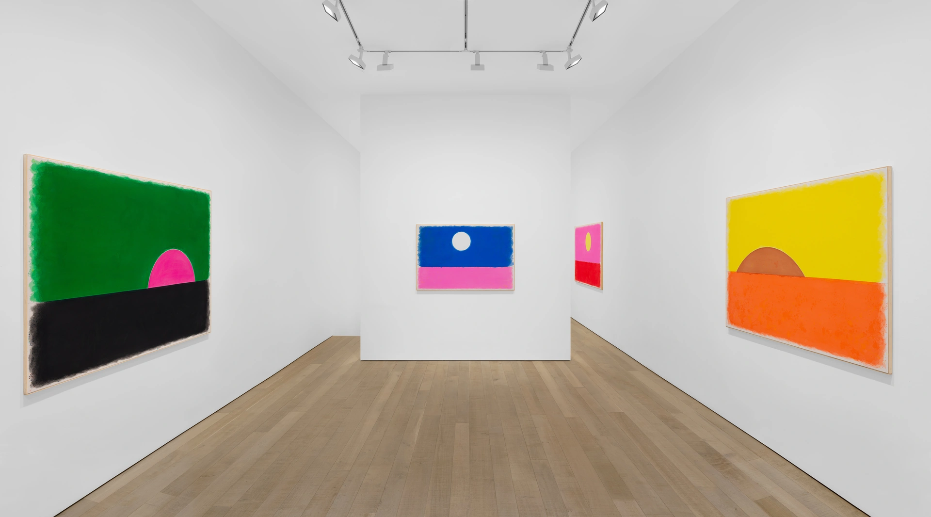 An art gallery interior featuring four abstract paintings in various colors displayed on white walls.
