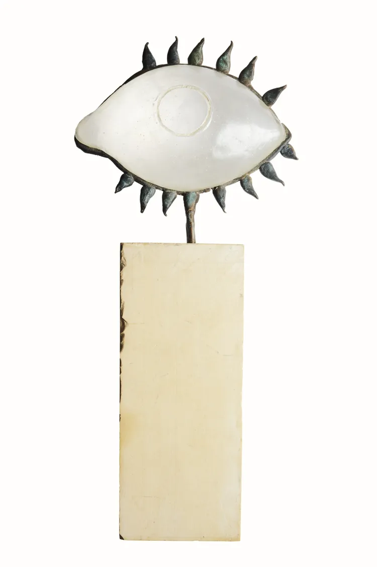 A sculpture of an eye with pointed edges sitting on a rectangular base.