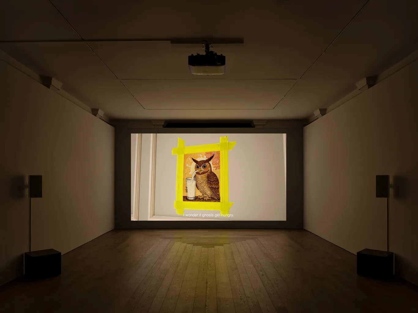An owl picture on a wall with yellow tape in a dimly lit room.