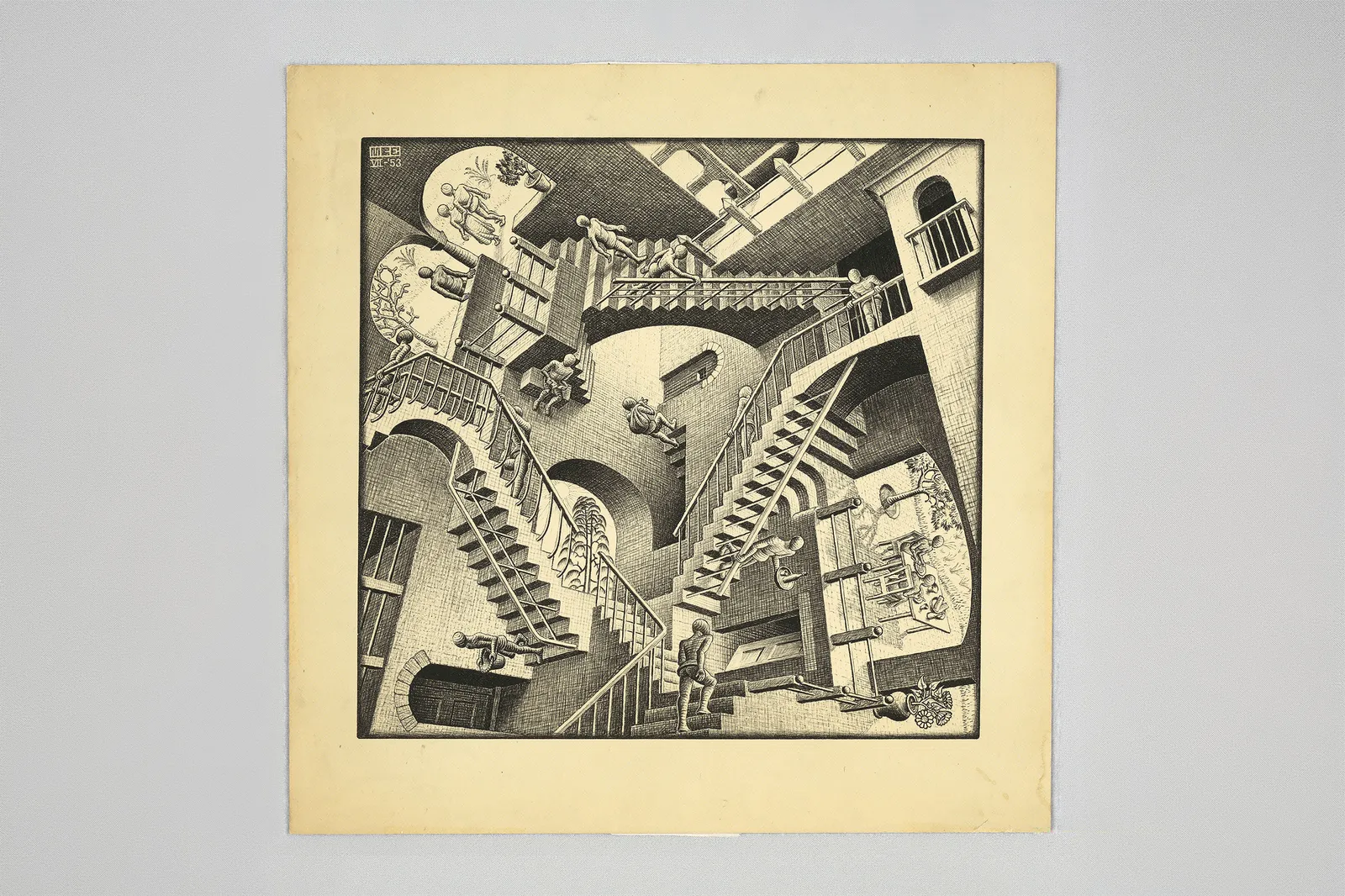 An intricate, surreal illustration featuring a series of staircases that lead in seemingly impossible directions, creating an optical illusion. The scene includes various architectural elements, such as arches and balconies, with figures interacting within the space.