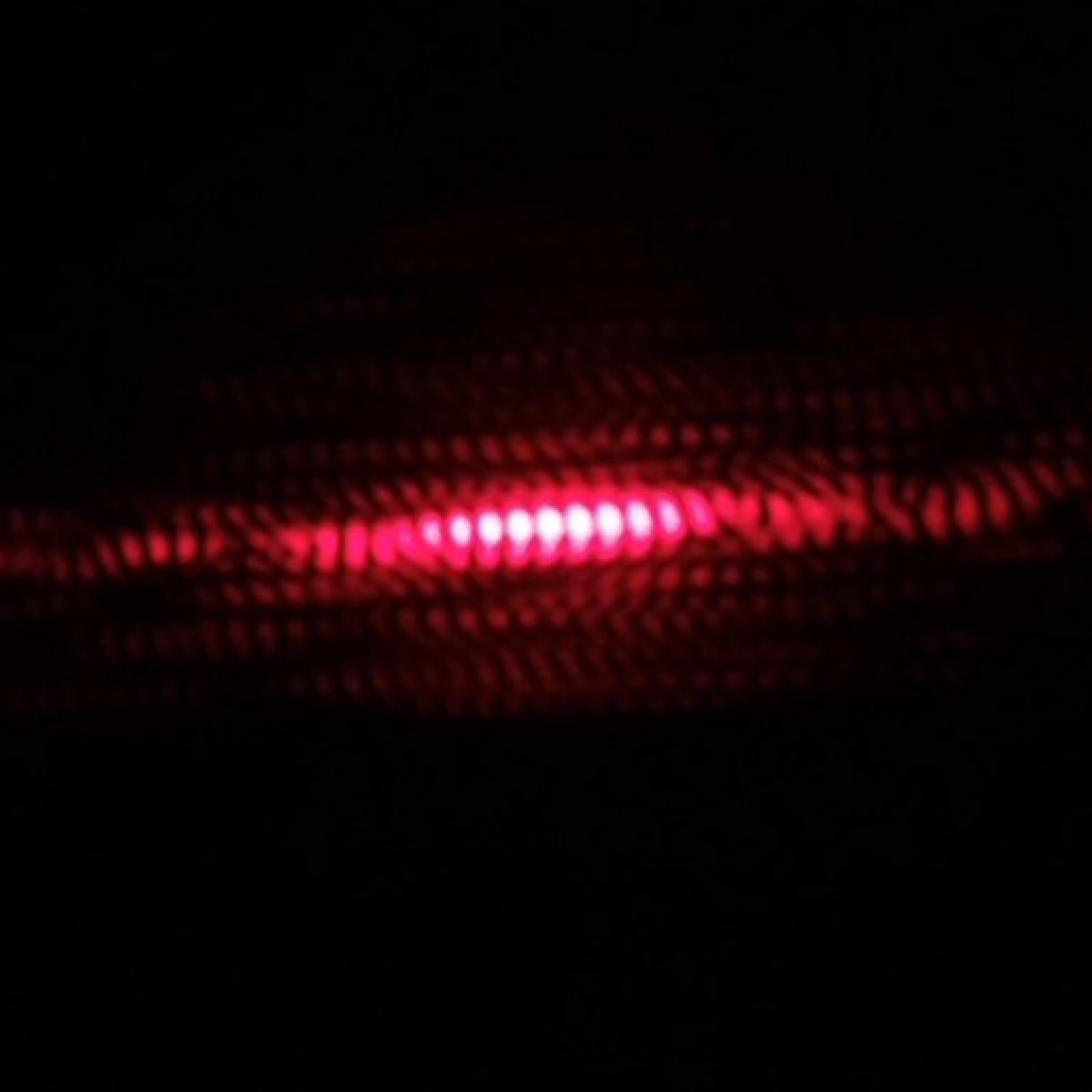 A red light source in a dark background, with patterns created by the light.