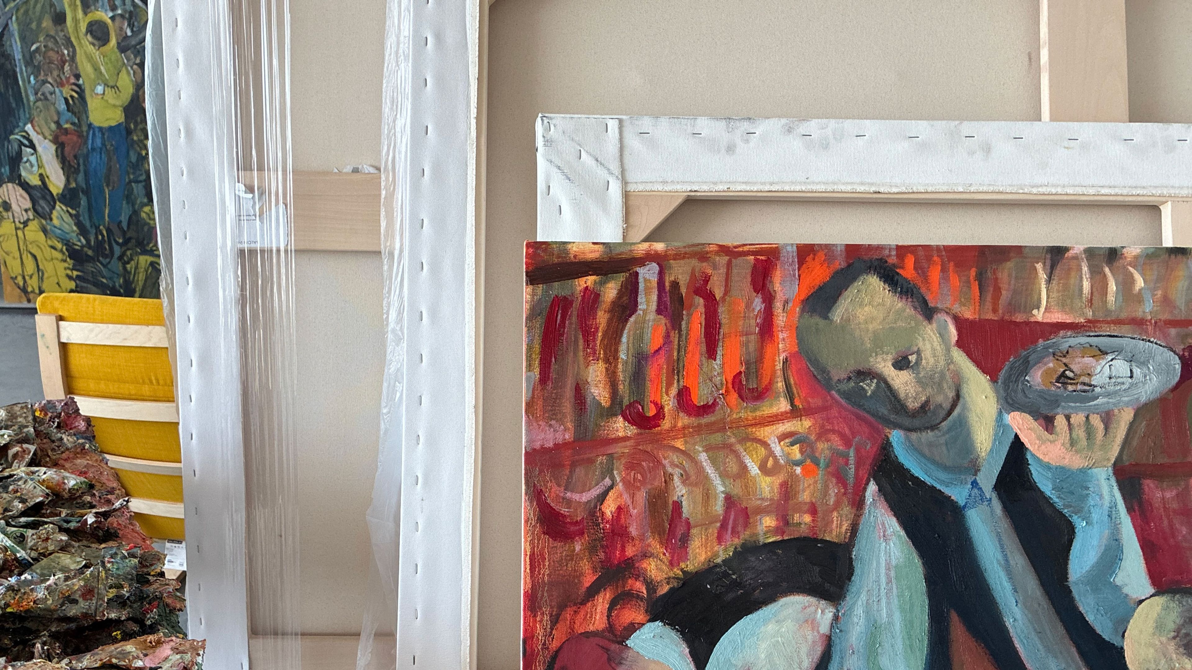 A painting of a man holding a plate, with an abstract setting and vibrant colors, surrounded by art supplies and other artworks in a studio. | 2026 David Zwirner