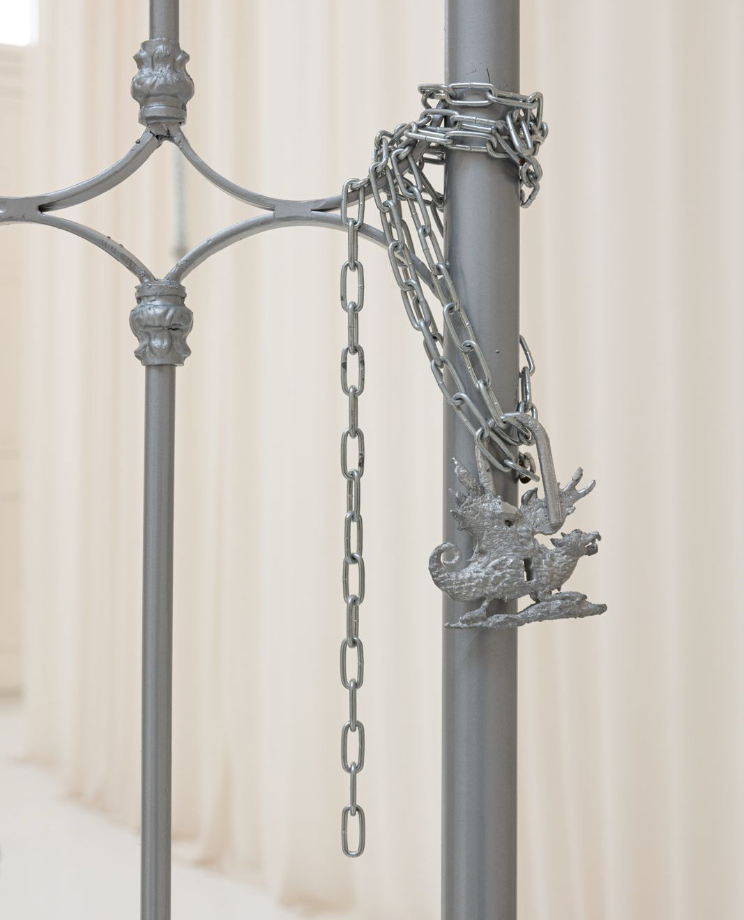 A grey metal pole with chains and a decorative dragon-like figure hanging from it.