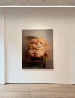 A softly lit gallery displays a warm-toned painting of a curled, reclining figure, creating an intimate, contemplative mood.